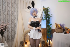 A woman in a bunny costume sitting on a bed.