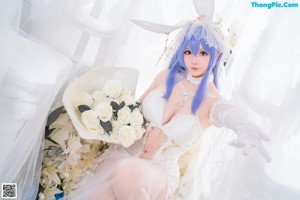 A woman in a white dress sitting on a bed of flowers.