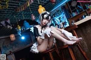 A woman in a maid outfit standing at a bar.