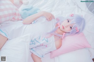 A girl in a pink dress sitting on a bed with stuffed animals.