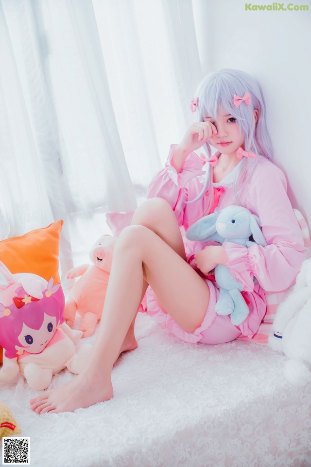 A woman sitting on a bed with stuffed animals.