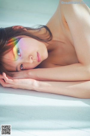 A woman in a pink bikini sitting on a wooden floor.