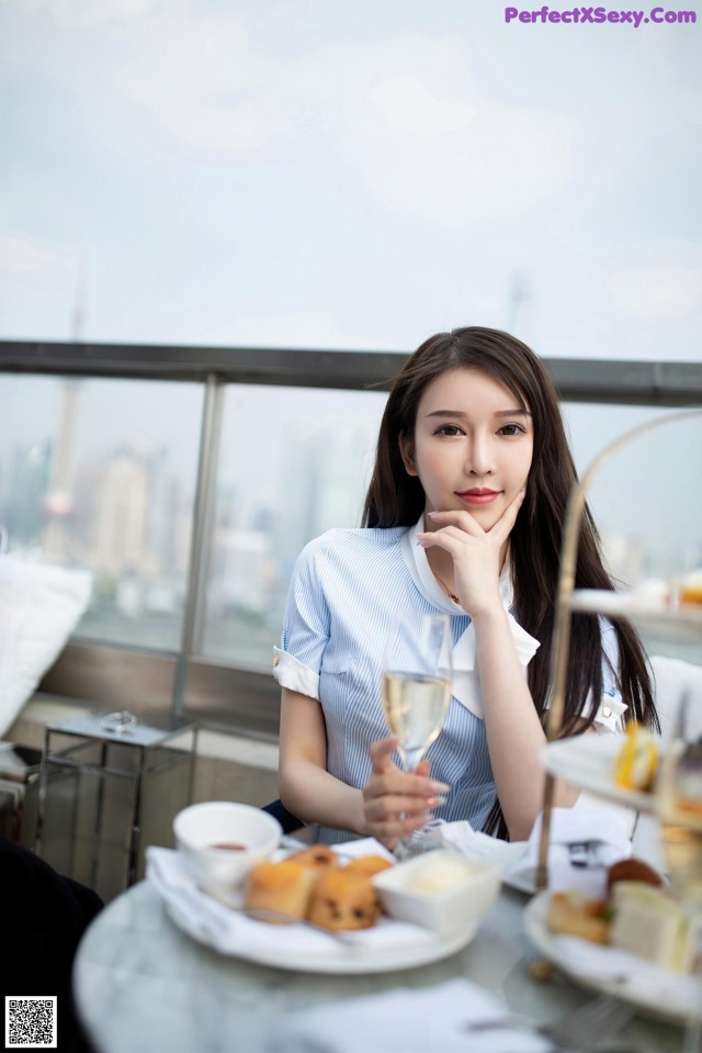 A woman sitting at a table with a glass of wine.