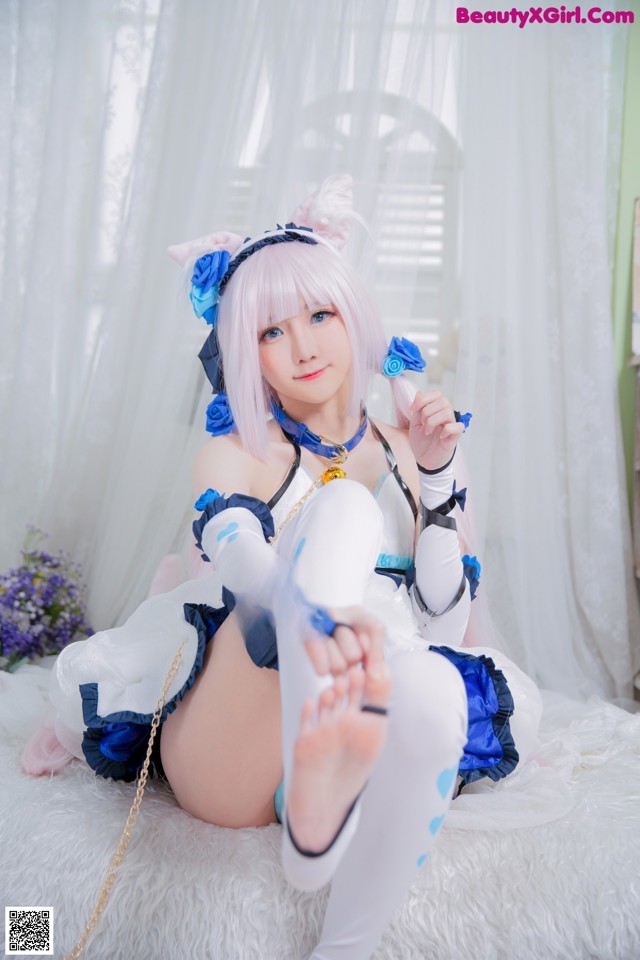 A woman in a white and blue outfit sitting on a white rug.