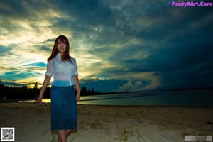A woman in a white dress is posing for the camera.