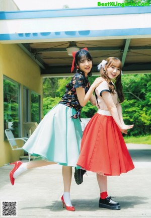 Two young women standing next to each other in front of a tree.