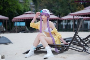 A woman in a yellow bikini holding a wand on a beach.