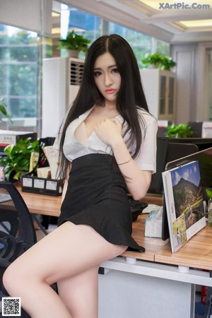 A woman in a white shirt and black skirt holding a book.
