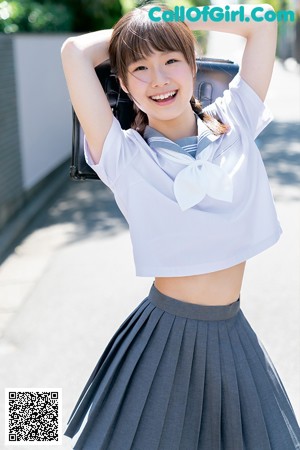 A young woman in a school uniform is posing for a picture.