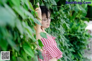 A woman wearing glasses and a red and white checkered shirt.