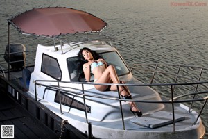 A naked woman sitting on the edge of a boat.