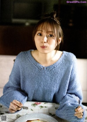 A woman with long brown hair sitting on the floor.