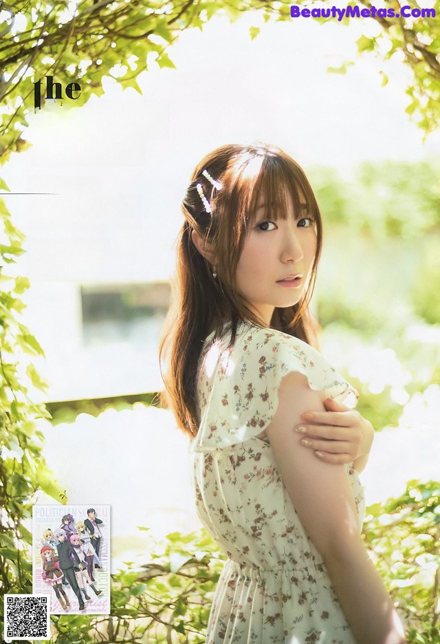 A woman in a white dress standing in front of a tree.