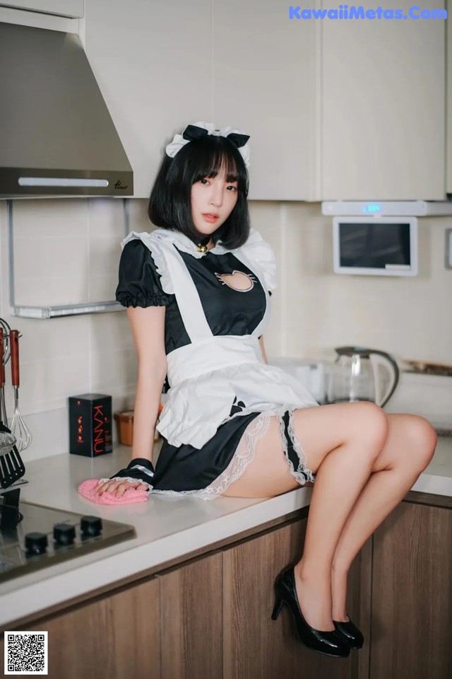 A woman in a maid outfit sitting on a kitchen counter.