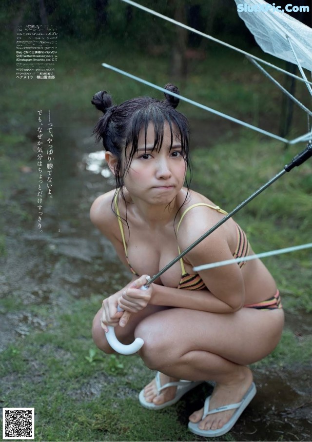 A woman in a bikini holding an umbrella in the rain.