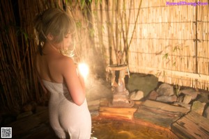 A woman in a white towel sitting on a wooden bench.