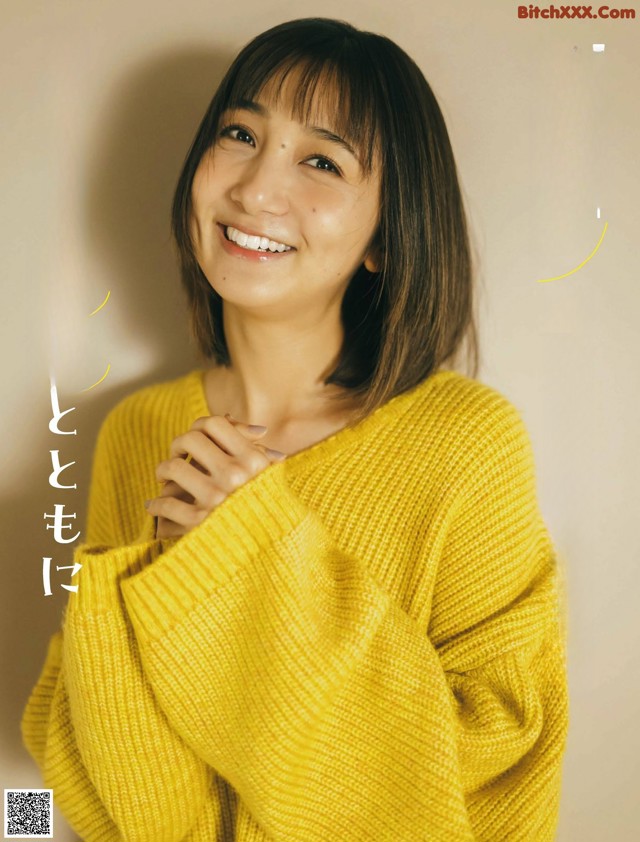 A woman in a yellow sweater smiles at the camera.