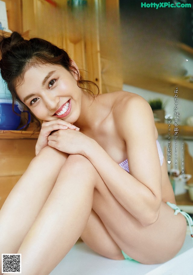 A woman in a bikini sitting on top of a bathtub.