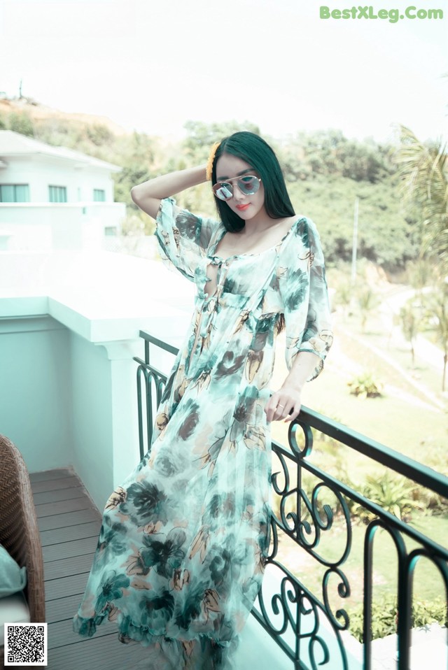 A woman in a long dress standing on a balcony.