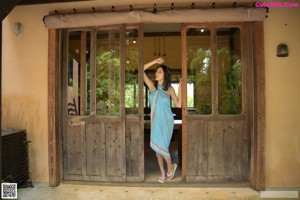 A naked woman standing in front of a wooden door.