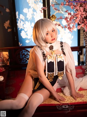 A woman sitting on top of a bed next to a lamp.