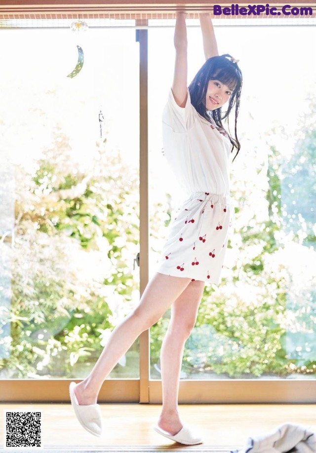 A woman in a white shirt and cherry print skirt posing for a picture.