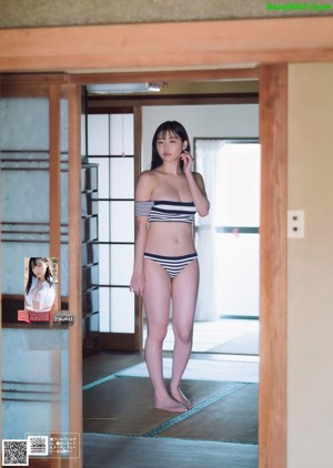 A woman in a white bikini standing next to a tree.