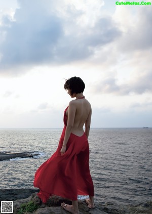 A woman in a red bathing suit standing on a beach.