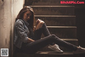 A woman leaning against a wall with graffiti on it.