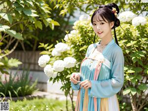 A woman in a blue and pink dress standing in front of white flowers.